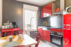 een keuken met rode kasten en een tafel en stoelen bij Et si on restait en Normandie ? in Caen