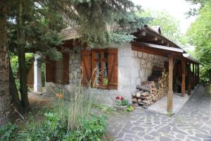 una casa de piedra con porche y un montón de madera en Garábi Udvarház en Garáb