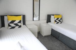 リバプールにあるBanksy House by Serviced Living Liverpoolの白と黄色の枕が備わる小さな部屋のベッド2台