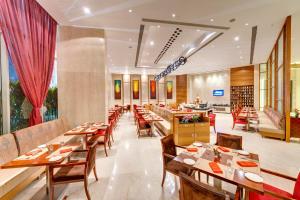 a dining room with wooden tables and chairs at Pride Plaza Hotel, Kolkata in Kolkata