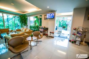 a living room with a couch and chairs and a tv at Kanavera Sriracha Hotel & Serviced Apartment in Si Racha