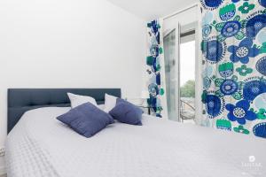 a bed with blue and white pillows and a window at Jantar Apartamenty - Perłowa Przystań in Kołobrzeg