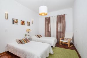 a white room with two beds and a chair at Casa Jacarandá in Silves