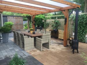 een patio met een houten pergola en een houten tafel en stoelen bij Rumah kita, bungalow met 2 slaapkamers in het mooie Drenthe in Erm