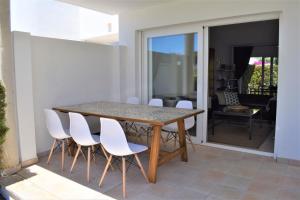 un patio con mesa de comedor y sillas blancas en Ground Floor with private garden Bellresguard en Puerto Pollensa