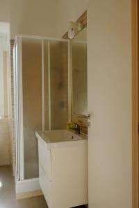 uma casa de banho branca com um lavatório e um chuveiro em B&B Napoli Leggendaria em Nápoles