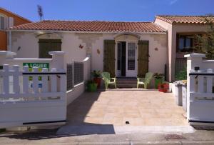 une maison avec une clôture blanche devant elle dans l'établissement Villa Relax de plain pied - Marseillan, à Marseillan