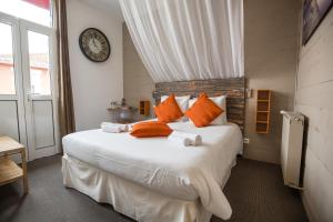 ein Schlafzimmer mit einem großen Bett mit orangefarbenen Kissen und einer Uhr in der Unterkunft Hôtel Familial L'Ostréi in Arcachon