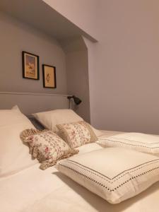 uma cama com lençóis brancos e almofadas em Arles Rental-Côté Forum. em Arles
