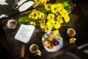 una mesa con dos platos de comida y flores y tazas de café en The Bali Boarding House, en Uluwatu