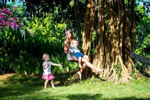 a woman and two children playing on a swing at The Bali Boarding House in Uluwatu