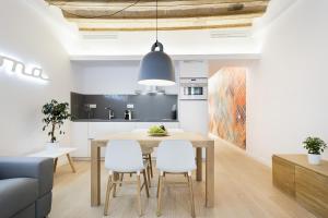 Ola Living Santa Anna في برشلونة: مطبخ وغرفة طعام مع طاولة خشبية وكراسي بيضاء