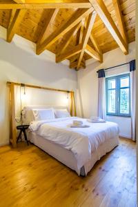 a bedroom with a large white bed with wooden ceilings at Villa Skyphos in Ammoudari +58 photos