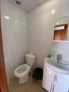 a white bathroom with a toilet and a sink at Guest House Mikhail in Adler