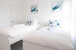 a white bedroom with two beds and a couch at The Comet - 5 separate beds & 3 bathrooms in Burton upon Trent