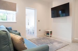 sala de estar con sofá y TV en la pared en The Comet - 5 separate beds & 3 bathrooms, en Burton upon Trent