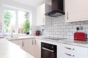 a kitchen with white cabinets and a red appliance at The Comet - 5 separate beds & 3 bathrooms in Burton upon Trent