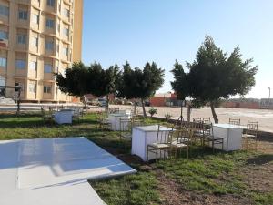 a group of tables and chairs in front of a building at Royal NJ Hotel in Borg El Arab