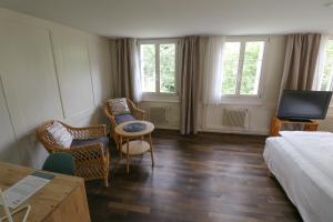 um quarto de hotel com uma cama e cadeiras e uma televisão em EMMA Bett und Bistro em Winterthur