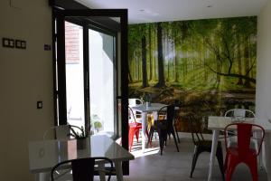 ein Restaurant mit Tischen und Stühlen und einem Wandbild von Bäumen in der Unterkunft ALBERGUE HOSTING DUERO in Pesquera de Duero