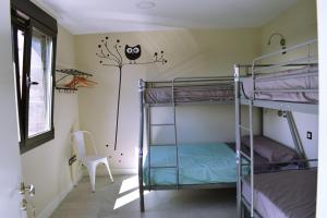 Pokój wieloosobowy z łóżkami piętrowymi i krzesłem w obiekcie ALBERGUE HOSTING DUERO w mieście Pesquera de Duero