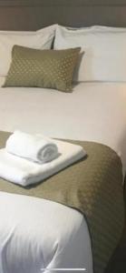 2 camas blancas con almohadas y una toalla. en Oak Lodge Portumna, en Portumna