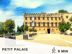 Un gran edificio de ladrillo con un reloj encima. en Aventure Avignonnaise - ROOFTOP TERRASSE - INTRAMUROS - CITY CENTER, en Aviñón