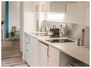Una cocina con gabinetes blancos y un fregadero. en Aventure Avignonnaise - ROOFTOP TERRASSE - INTRAMUROS - CITY CENTER, en Aviñón