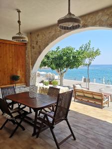 een eetkamer met een tafel en stoelen en de oceaan bij Relax Seaside House in Charaki