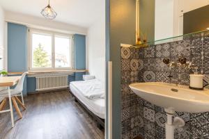 ein Bad mit einem Waschbecken und einem Bett in der Unterkunft Hostel by Hyve Basel in Basel