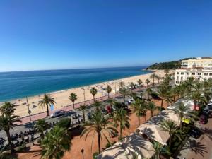 a beach with tents and palm trees and the ocean at Mediterranean apartment in Lloret de Mar next to the Sea in Lloret de Mar