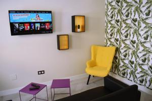 salon z fioletowymi i żółtymi krzesłami oraz telewizorem w obiekcie ALBERGUE HOSTING DUERO w mieście Pesquera de Duero