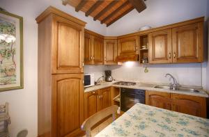 una cocina con armarios de madera y una mesa. en La Renaia en Cortona