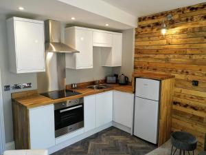 a kitchen with white cabinets and a wooden wall at Derby Den by Cliftonvalley Apartments in Bristol