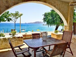 een tafel en stoelen op een patio met uitzicht op de oceaan bij Relax Seaside House in Charaki