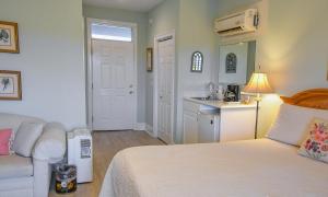 a bedroom with a white bed and a kitchen at The Sunset Inn in Sunset Beach