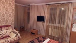 a living room with a couch and a tv and a window at Margarita Guest House in Sochi