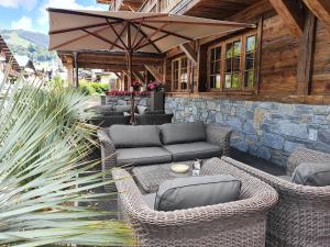 un patio al aire libre con muebles de mimbre y sombrilla en Le Chalet Blanc, en Megève