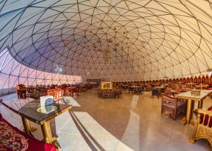 a large room with a large dome with tables and chairs at Memories Aicha Luxury Camp in Wadi Rum