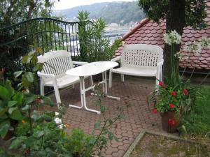 2 sillas blancas y una mesa en el patio en Pension Elbblick Sabine Zuschke, en Meißen