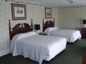 two beds in a hotel room with white sheets at Atlantic Hotel, Inc in Ocean City