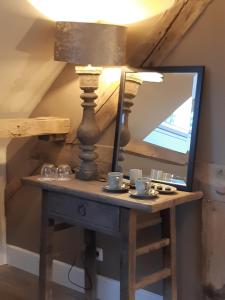 a table with a lamp and a mirror on it at B&B Langeveldemolen in Merchtem
