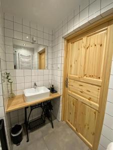 a bathroom with a sink and a wooden door at Komoda Tykocin in Tykocin