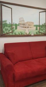 - un canapé rouge dans une chambre avec une photo du Colisée dans l'établissement Via Palestro 56 Apartment, à Rome