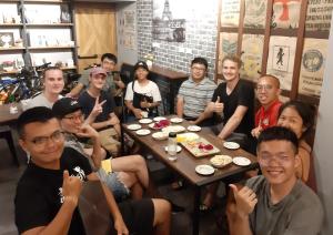 eine Gruppe von Menschen, die um einen Tisch sitzen in der Unterkunft 清淨背包客棧-民權館Quiet Hostel - Minquan Inn in Tainan
