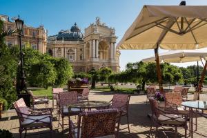 a group of chairs and tables with an umbrella in front of a building at Mozart Hotel in Odesa