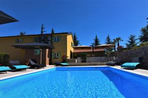 a swimming pool in front of a house at Letorina rooms and apartments with pool in Matulji