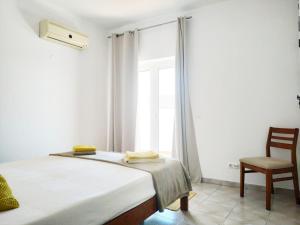 een slaapkamer met een bed, een stoel en een raam bij Tavira Lovers - City Centre Apartments in Tavira