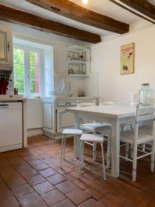 - une cuisine avec une table et des chaises blanches dans l'établissement CHARMANTE MAISON DE CAMPAGNE DU 17ème siècle à Lilette avec Jacuzzi et proche rivière, à Buxeuil