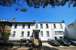 un edificio bianco con macchine parcheggiate di fronte di Villa Nova a Saint Helier Jersey